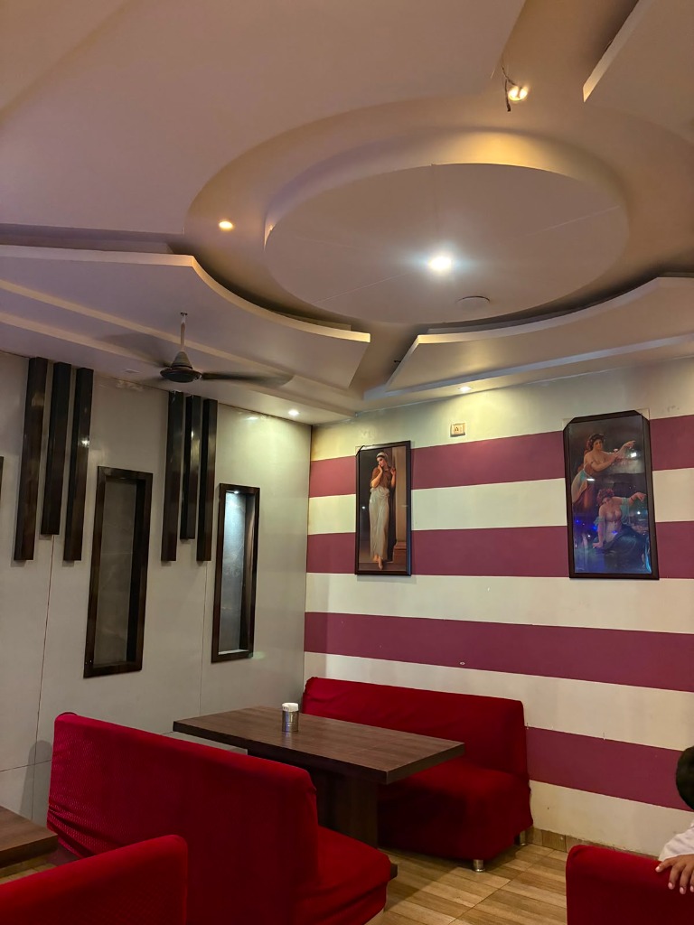 Air-conditioned indoor dining hall with circular cove ceiling, warm downlights, and red velvet booth seating at Shah Junction Villa